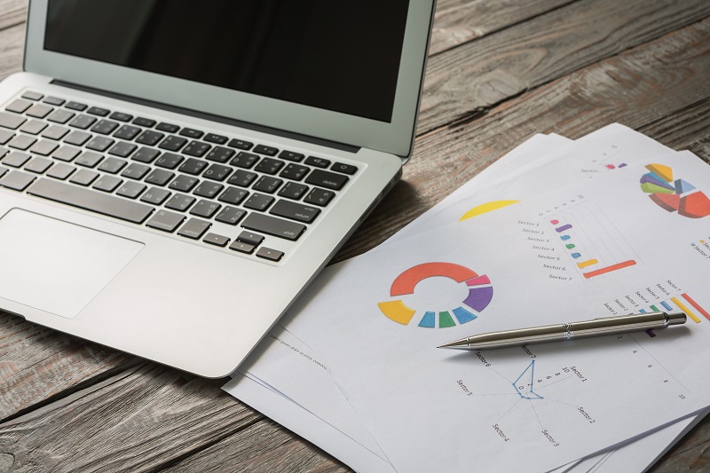 An image of a laptop sitting alongside documents containing financial data. Business Development from Van Middlesworth and Company