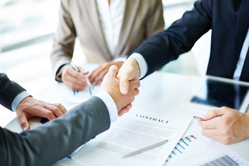 An image of two financial professionals shaking hands over legal documents. Trusts with Van Middlesworth and Company.